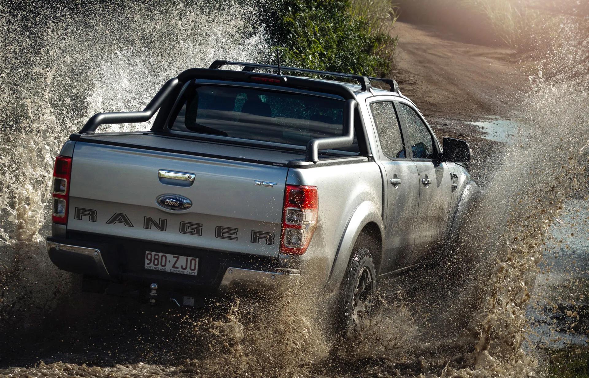 Silver Ford Ranger driving through a muddy water crossing on an off-road trail, fitted with an EGR sports bar